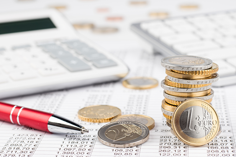 Taschenrechner, Stift und Euro-Münzen auf einer Abrechnungsübersicht