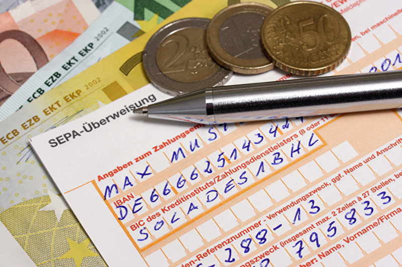 SEPA-Überweisungsformular mit Euro-Münzen und Kugelschreiber